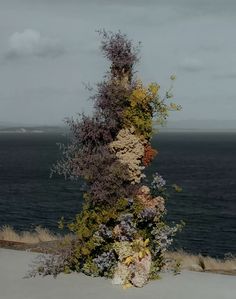 there is a very tall vase with flowers on it by the water's edge