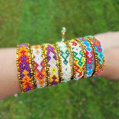 a person's arm with bracelets on it and a green field in the background