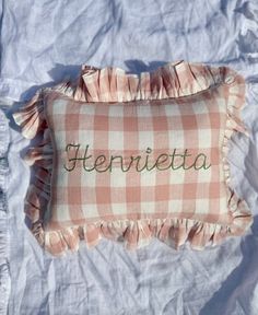 a pink and white checkered pillow with the word hermieta embroidered on it