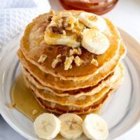 a stack of pancakes topped with bananas and nuts