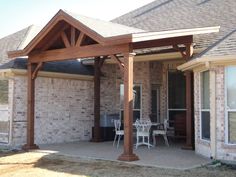 a covered patio with chairs and table in front of it