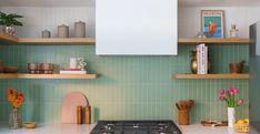 a stove top oven sitting inside of a kitchen next to wooden shelves filled with pots and pans