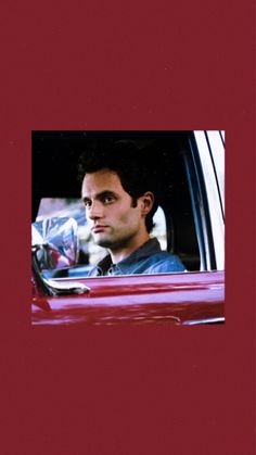 a man sitting in the passenger seat of a red car