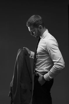 black and white photograph of a man looking down at his suit on a hanger