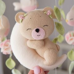 a teddy bear hanging from a string with pink flowers on it's head and eyes