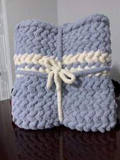 two blue crocheted blankets tied together on a table