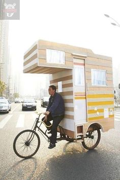 a man riding a bike with a small house on the back