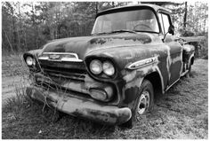 an old truck is parked in the grass