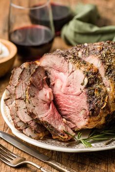 a piece of roast beef on a plate next to a glass of wine