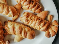 several croissants on a white plate with one cut in the shape of a dog