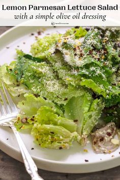 a white plate topped with lettuce salad next to a fork