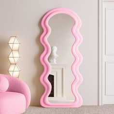 a pink mirror sitting on top of a white floor next to a chair and vase