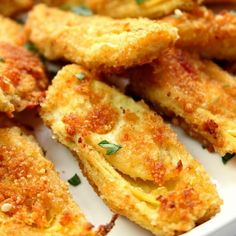 some fried food on a white plate with parmesan cheese and seasoning sprinkles