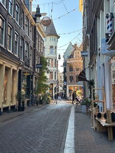 an empty city street with shops and people walking on the sidewalks in front of buildings