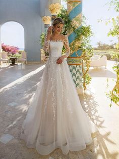 a woman in a wedding dress posing for the camera with her hand on her hip