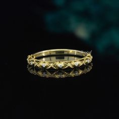 a gold wedding ring with diamonds on it's side, against a black background