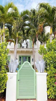 a green door is in front of some palm trees