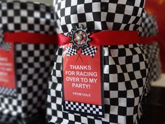 two black and white checkered bags with red ribbon tied around the edges, one has a thank for racing over to my party tag on it