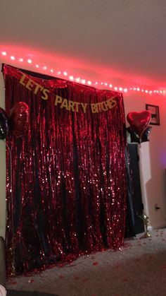 a party room with balloons and streamers on the wall, red tinsel curtains