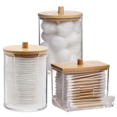 two clear containers with wooden lids and some white balls in the bottom one is filled with cotton swabs