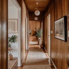 a long hallway with wood paneling and potted plants