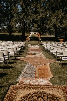 an outdoor ceremony setup with chairs and rugs