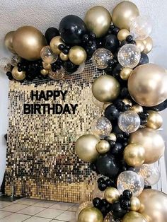 a happy birthday balloon arch with black, gold and silver balloons