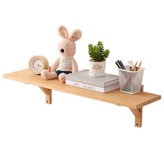 a stuffed animal sitting on top of a wooden shelf next to a potted plant