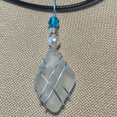 a piece of glass sitting on top of a black cord with a blue bead