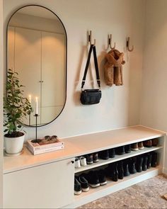 shoes are lined up against the wall in front of a mirror and coat rack with hooks on it