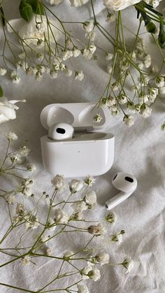 an apple airpods sitting on top of a white table cloth next to some flowers