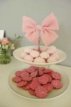 two tiered trays with pink and white cookies on them, each topped with a large bow