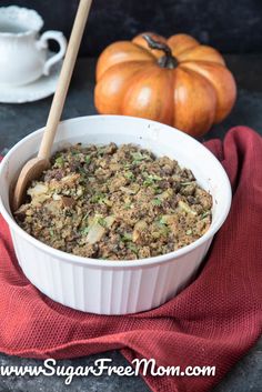 a white bowl filled with stuffing next to two pumpkins