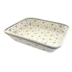 a white and blue rectangular dish on a white surface with small flowers in the center