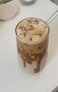 an iced drink with ice cubes in it on a white counter top next to a spoon