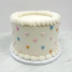 a cake with white frosting and multicolored butterflies on it sitting on a table