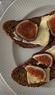 two pieces of bread with cheese and figs on them sitting on a white plate