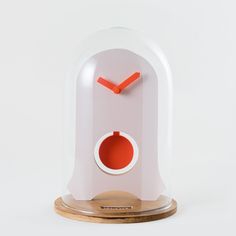 a white clock with an orange face on a wooden base and wood stand against a white background