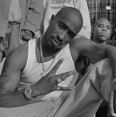 a black and white photo of a man with tattoos on his arm sitting in front of other men