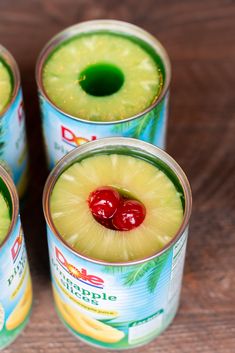 four cans of pineapple drink with cherries on top