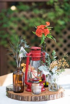 an arrangement of flowers and vases on a wooden table with greenery in the background