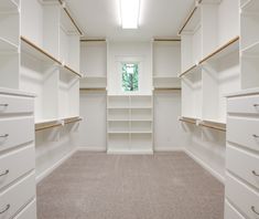 an empty walk - in closet with white shelves and beige carpeted flooring is shown