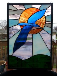 a close up of a stained glass window with a bird in the sky on it