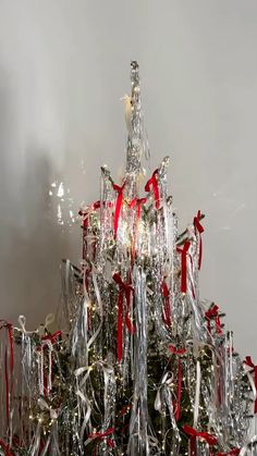 a silver christmas tree with red bows and lights