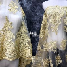 two mannequins dressed in gold and white dresses with golden lace on them