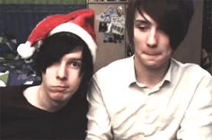 two young men sitting next to each other in front of a christmas hat on their head