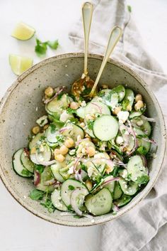 a bowl filled with cucumbers, onions and garbanzo beans on top of a table