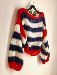 a red, white and blue striped sweater hanging on a clothes hanger next to a wall