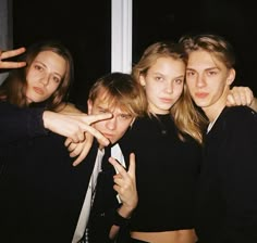 four people posing for the camera with their fingers in the air and one pointing at something