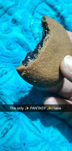 a hand holding a half eaten cookie in the shape of a shark's mouth